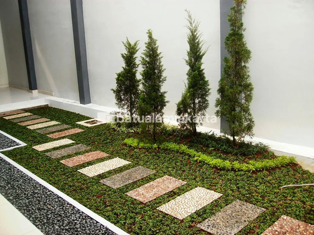 Stepping batu koral sikat pada taman minimalis dengan kombinasi rumput hijau.